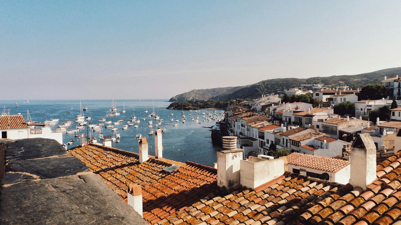 Whitewashed houses and terracotta roofs above a harbour on the Spanish coast