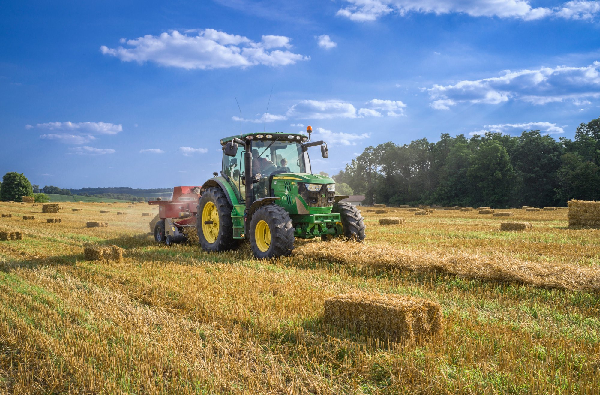 Tractor baling hay in a field at harvest